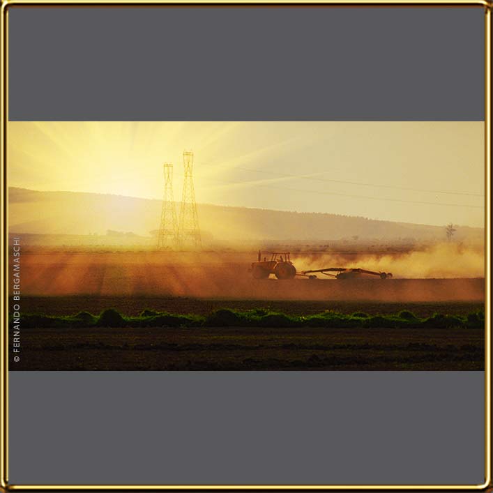 Tractor ploughing with power-transmission towers back.
